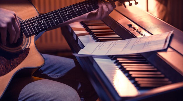 persona tocando guitarra sobre un piano