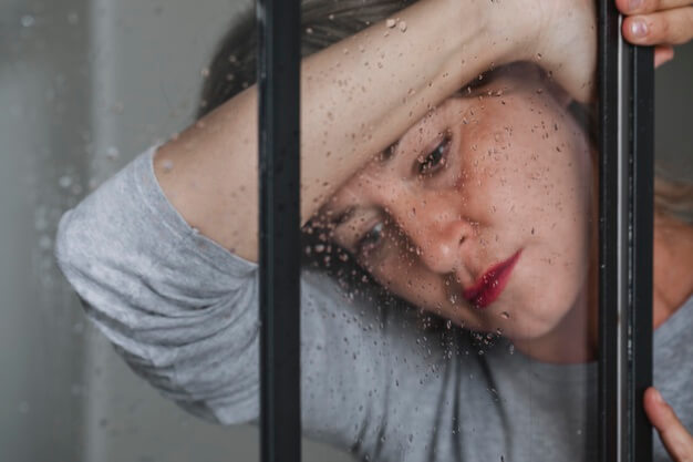 mujer triste recostada sobre ventana