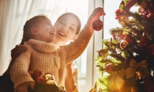 mamá e hija colocando adornos al arbol de navidad