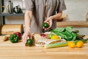 Una persona en ropa casual preparando un desayuno vegetariano por la mesa de la cocina