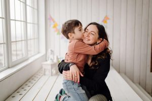 Niño abrazando a su mamá después de darle un regalo en el día de la madre.